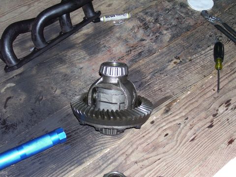1991 Ford Bronco - A differential and exhaust manifold are laid out on a wooden workbench with various tools nearby.