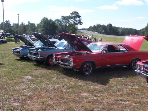 1973 Ford Ranchero - Several classic cars are lined up with their hoods open at an outdoor event.
