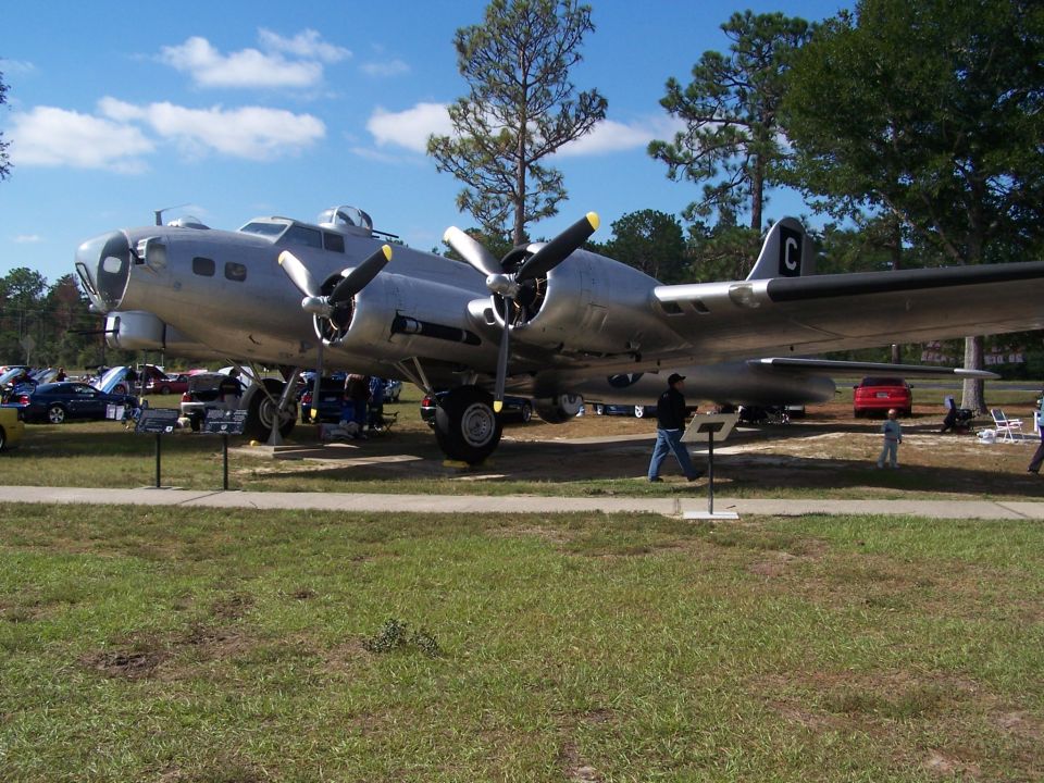 B-17 Flying Fortress airplane on display with cars parked in background