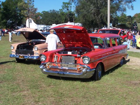 1973 Ford Ranchero - A red 1957 station wagon is displayed with its hood open, parked next to another classic car at an outdoor event.