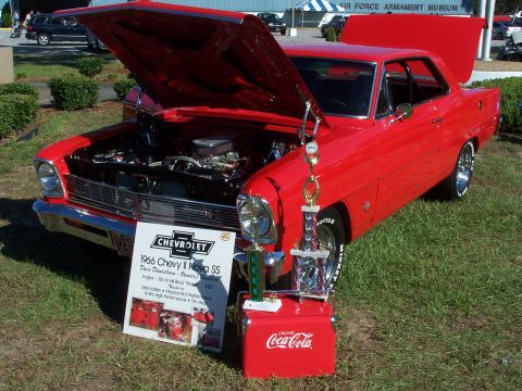 1973 Ford Ranchero - A red 1966 Chevrolet Nova SS is displayed with its hoods open, accompanied by trophies and a Coca-Cola cooler.