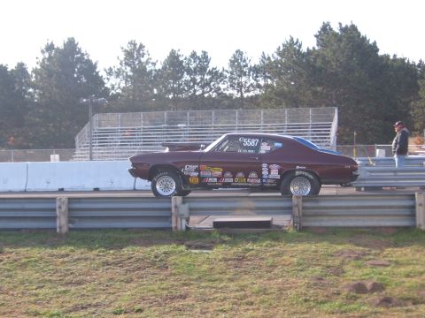 1989 Ford Mustang - A drag racing car sits on the track, adorned with numerous sponsor decals.