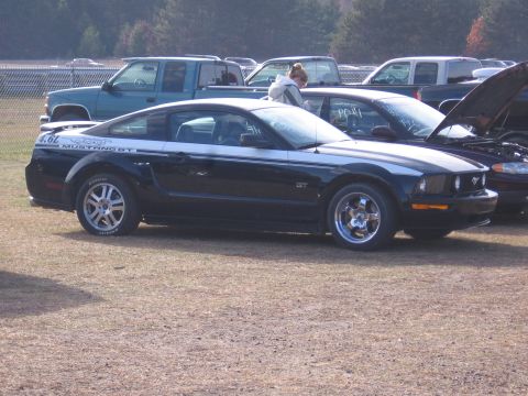 1989 Ford Mustang - Side view of a black Ford Mustang GT with silver racing stripes and aftermarket wheels.