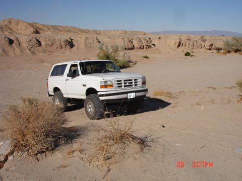 1996 Ford Bronco - A white Ford Bronco is parked in a dry, desert environment under a clear blue sky.