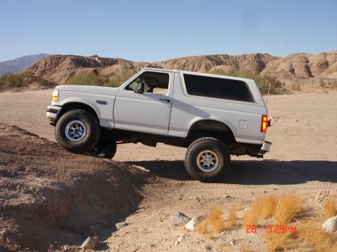 1996 Ford Bronco - 1996 Ford Bronco navigates a dirt trail in a desert landscape.