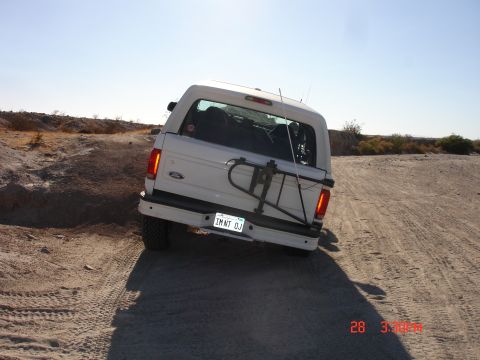 1996 Ford Bronco - 1996 Ford Bronco navigating a dusty off-road trail under a clear blue sky.
