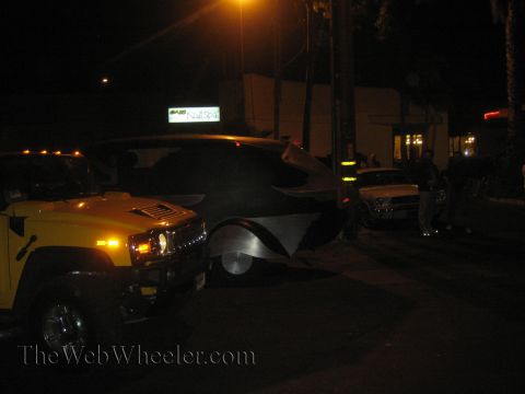 1968 Ford Mustang - A yellow Hummer H2 and a custom black vehicle are parked on a street at night, with a building and other cars in the background.