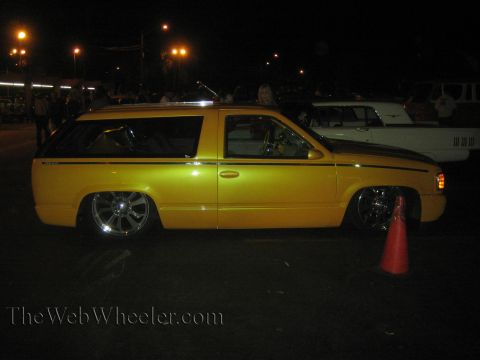 1968 Ford Mustang - A customized yellow SUV sits low to the ground under the night sky, with a classic white car parked behind it.