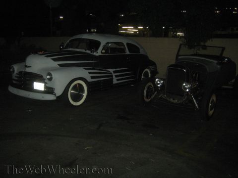 1968 Ford Mustang - Two vintage hot rod cars are parked side-by-side at night, illuminated by artificial lights.
