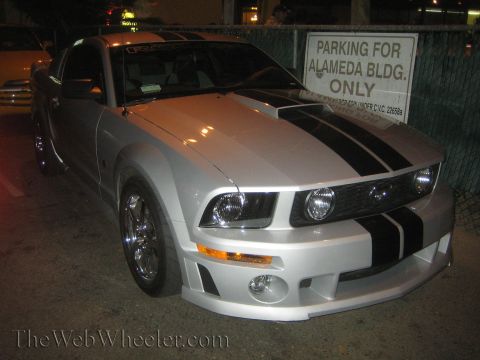 1968 Ford Mustang - Silver Ford Mustang with black racing stripes parked at night.