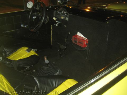 1968 Ford Mustang - The interior of a car shows black seats with yellow inserts and a manual transmission shifter.