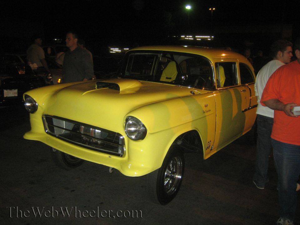 Yellow 1955 Chevrolet sedan delivery drag car with scoop on hood and racing seats visible