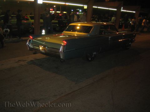 1968 Ford Mustang - A classic Cadillac is parked at night, with other vehicles and people in the background.