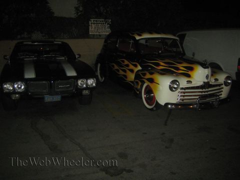 1968 Ford Mustang - A custom 1946 Ford hot rod with flame paint is parked next to a black car.