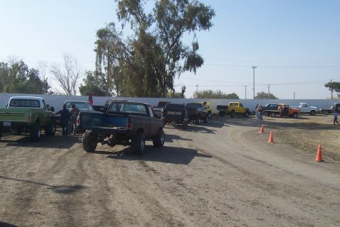 1994 Ford F-150 - A collection of modified pickup trucks are gathered on a dusty outdoor lot.