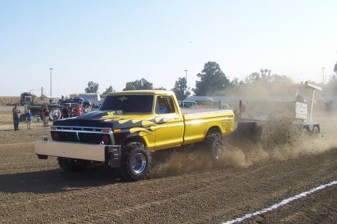 1994 Ford F-150 - Modified pickup truck competes in a pull event, kicking up dust as it drags a sled.