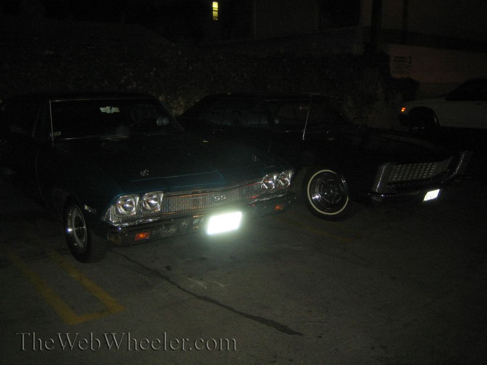 Dark green 1969 Chevrolet Chevelle SS parked next to a dark car, front view at night