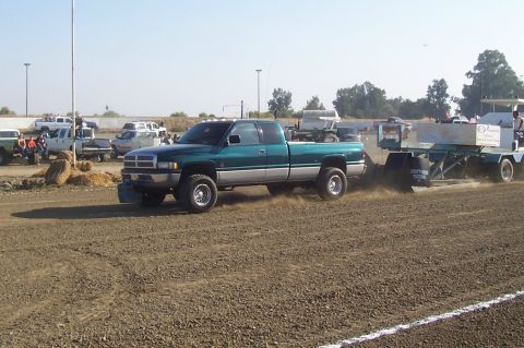 1994 Ford F-150 - A Dodge Ram pickup truck competes in a sled pull event, kicking up dust as it moves forward.