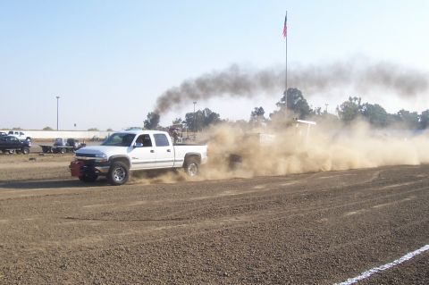 1994 Ford F-150 - A white pickup truck competes in a pull event, emitting dark smoke.