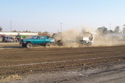 1994 Ford F-150 - Modified sedan competes in a pull event, kicking up dust as it drags a sled across the dirt track.