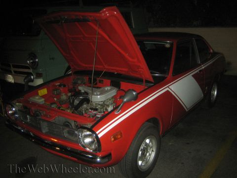 1968 Ford Mustang - A red coupe with white racing stripes is parked with its hood open, revealing the engine bay.
