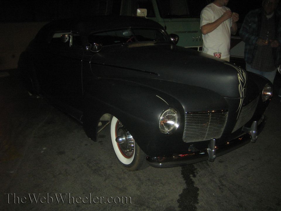 Black 1940s coupe hot rod with wide whitewall tires and chrome grille