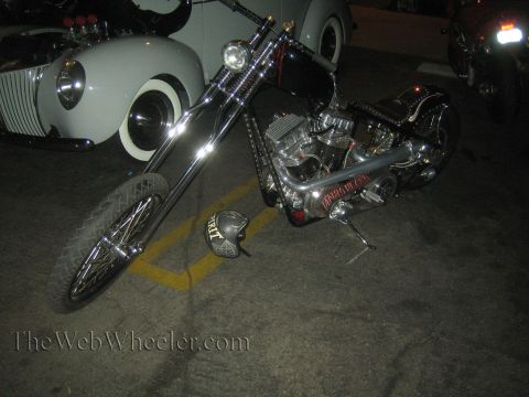 1968 Ford Mustang - A custom chopper motorcycle is parked next to a vintage car, with a helmet resting on the ground.
