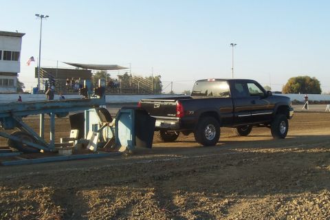 1994 Ford F-150 - A black pickup truck is seen from the side, participating in a pull event on a dirt track.