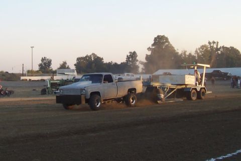 1994 Ford F-150 - A modified pickup truck competes in a pulling event, dragging a weighted sled across the dirt track.