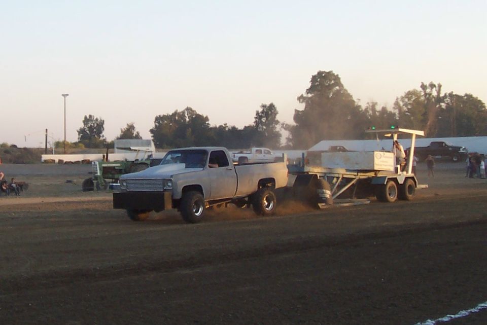 Gray pickup truck with a modified front end pulling a weighted sled