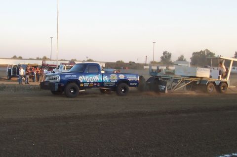 1994 Ford F-150 - Blue pickup truck competes in a pulling event, dragging a sled across a dirt track.