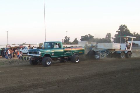 1994 Ford F-150 - A modified green pickup truck pulls a trailer across a dirt track.
