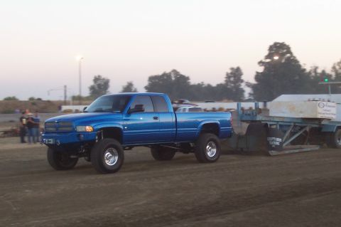 1994 Ford F-150 - A blue Dodge Ram pickup truck is seen from the side, towing a trailer loaded with concrete blocks.