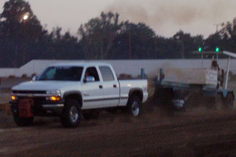 1994 Ford F-150 - A white pickup truck is seen towing a trailer with a person on it, kicking up dust.