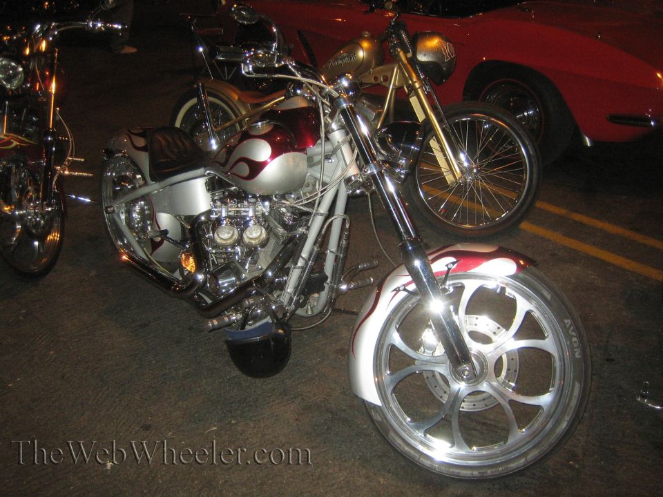 Front view of a custom motorcycle with silver and red flame paint and a large spoked wheel