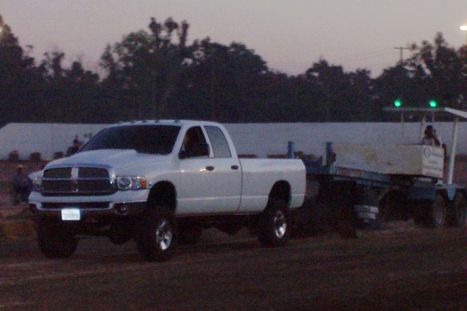 White Dodge Ram pickup truck towing a trailer with green lights on top