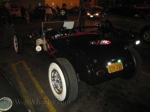 1968 Ford Mustang - A black hot rod with flame decals and white wall tires is parked at night.
