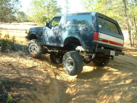 1995 Ford Bronco - This lifted 1995 Ford Bronco tackles challenging sandy terrain with its aggressive off-road tires and modified suspension.