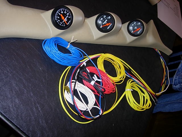 Tan triple gauge pod with Auto Meter gauges beside coiled wiring bundles