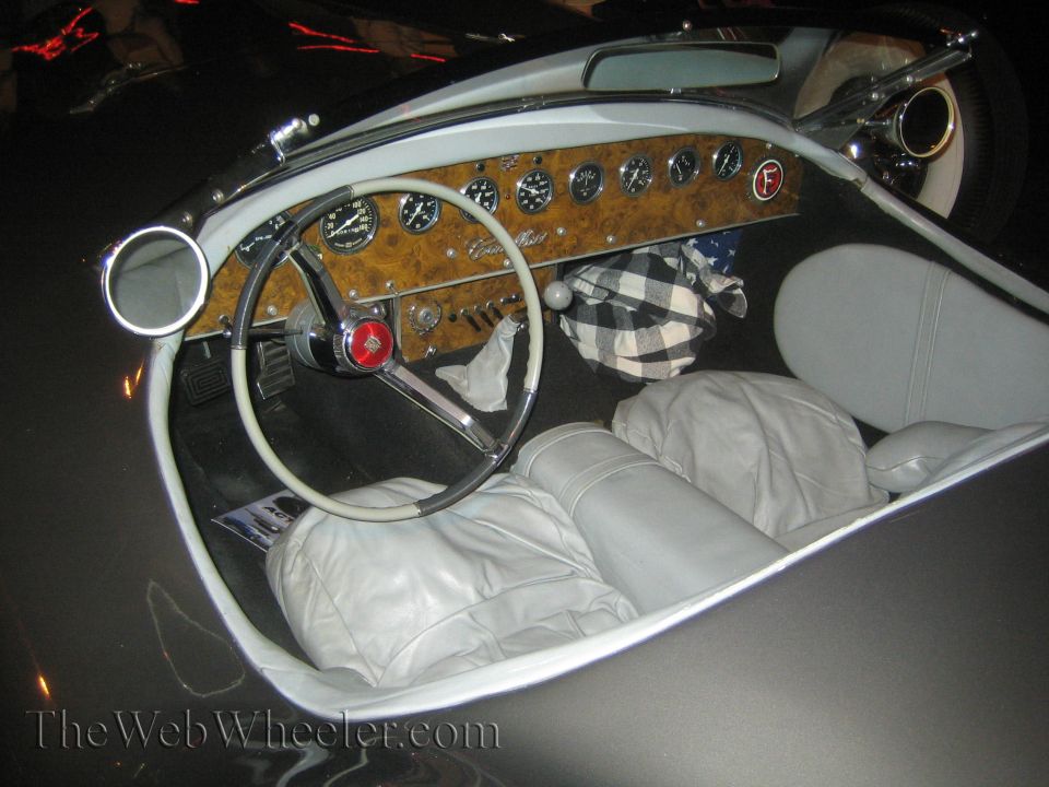 Interior view of a classic car with woodgrain dash, gauges, and white steering wheel
