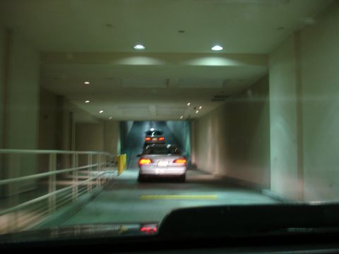 1993 Ford Taurus - A silver sedan is seen from behind as it drives through a brightly lit tunnel, with another vehicle following closely.