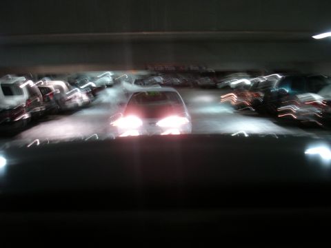 1993 Ford Taurus - A car with its headlights on is visible in a dimly lit parking garage, with motion blur affecting the image.