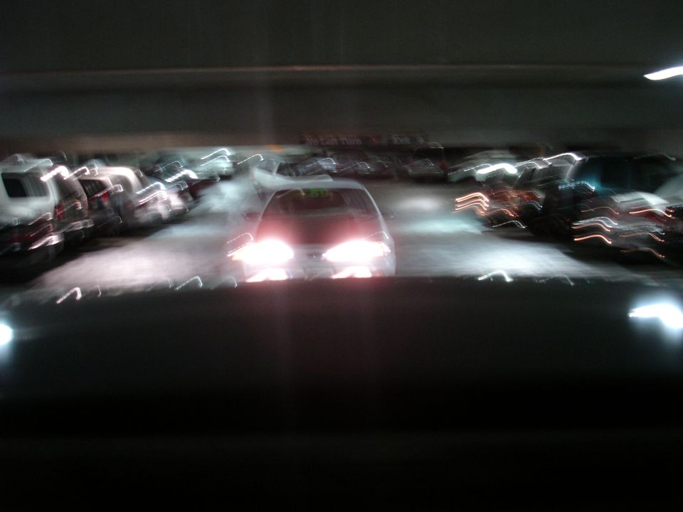 Car with headlights on in a parking garage, blurry motion