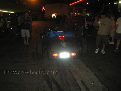 1968 Ford Mustang - A custom hot rod sits on a dirt surface at night, with people gathered around.