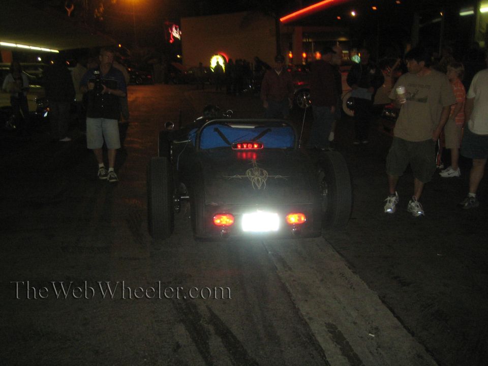 Rear view of a black hot rod with custom pinstriping and red taillights