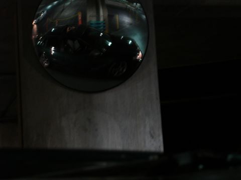 1993 Ford Taurus - A dark sedan is reflected in a convex mirror, likely in a parking garage at night.