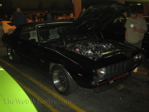 1968 Ford Mustang - Black 1969 Chevrolet Camaro parked with its hood open, revealing the engine bay.