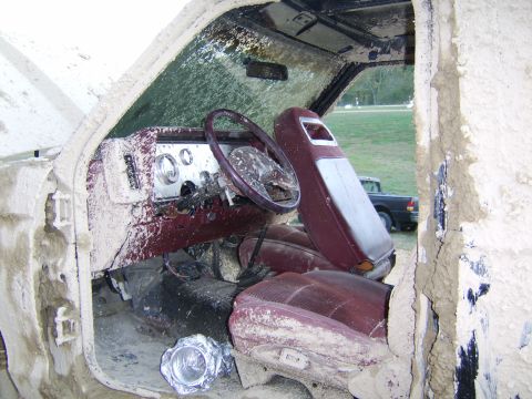 1986 Ford Ranger - The interior of a heavily mud-caked truck, with a second vehicle visible through the open door.