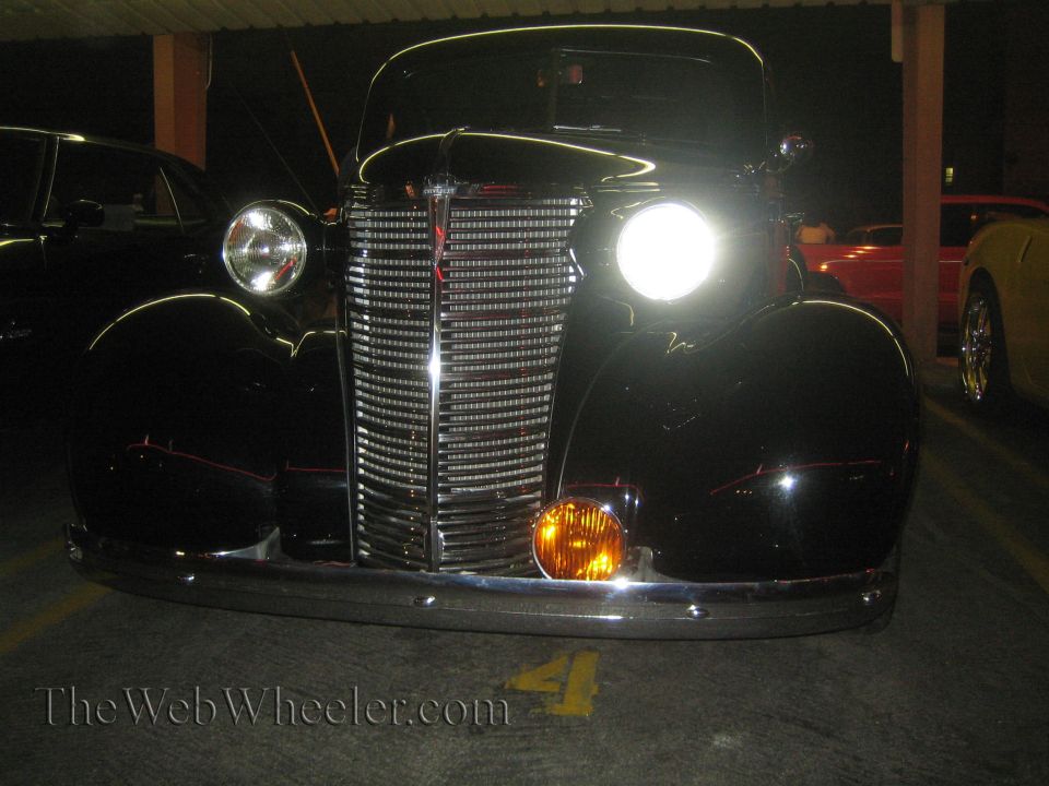 front view of a black vintage car with a chrome grille and round headlights