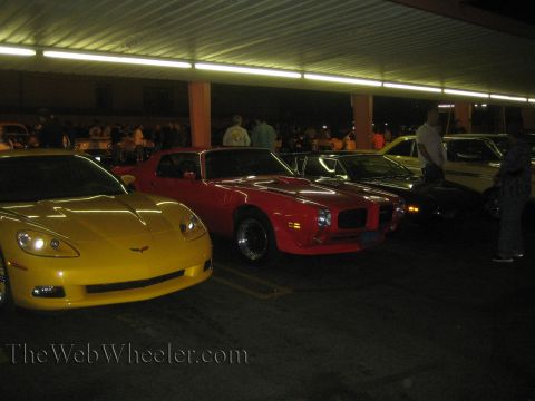 1968 Ford Mustang - Several cars are parked in a lot, including a red muscle car and a yellow sports car.